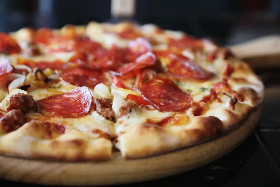 Pizza sa ljutom salamom na drvenoj dasci