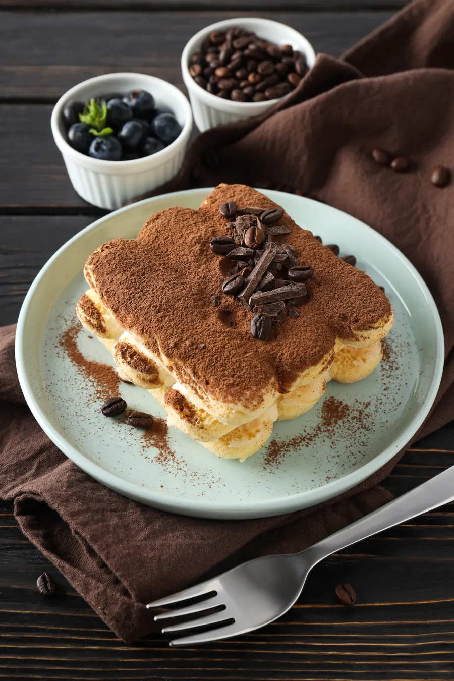 Tiramisu posut kakaom i zrnima kafe na tanjiru, pored viljuška